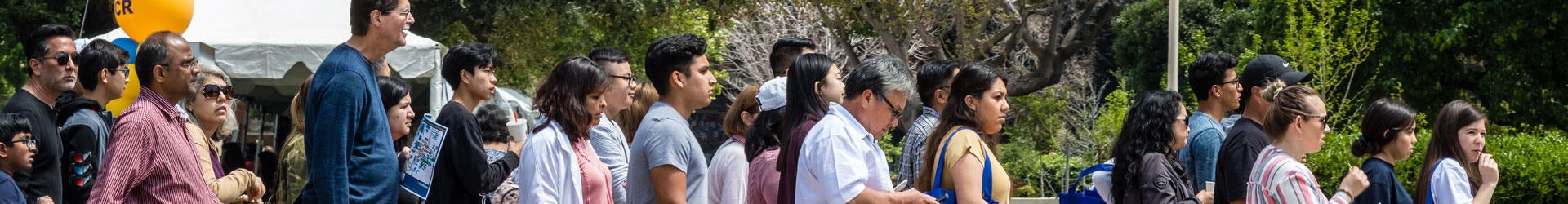 A large group of visitors is lead on a tour of the UCR campus